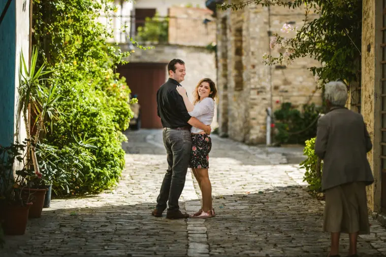 Couple standing on a cobbled lane as an elderly villager walks past in Lefkara