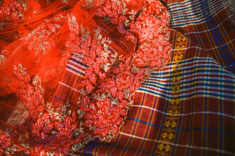 Close-up of a red embroidered sari with sequinned floral detail and a tartan-style border