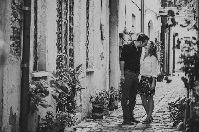 Black-and-white photo of the couple standing close in a plant-lined alley