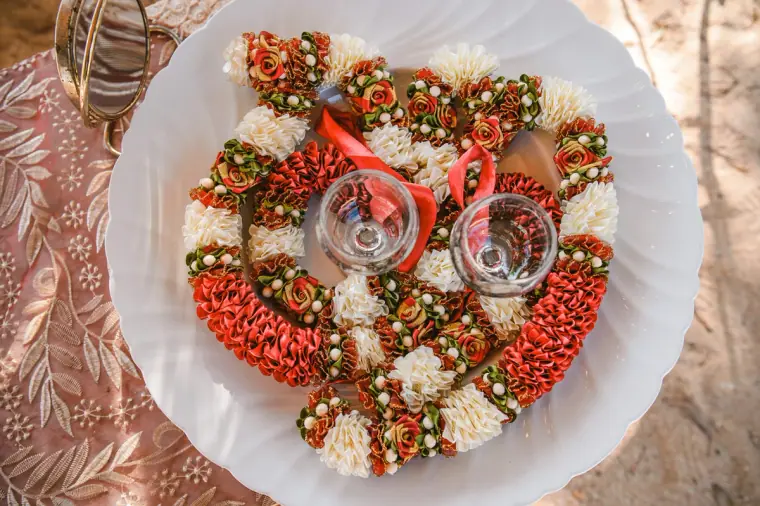 Plate of red and white flower garlands with two glasses, ready for the ceremony