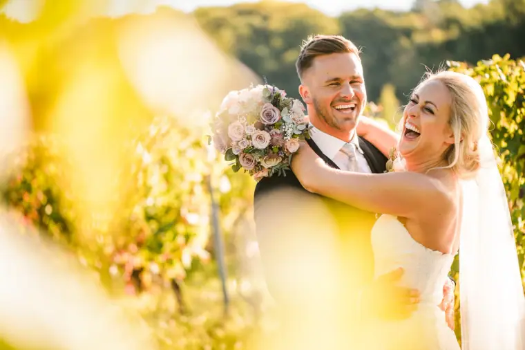 Sarah and Joe laughing together among sunlit vines at Chateau Rigaud, France