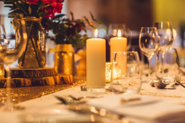 Pillar candles and red roses on a log slice on a reception table
