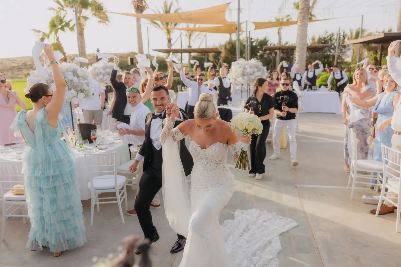 Bride and groom dancing into the reception between tables as guests cheer