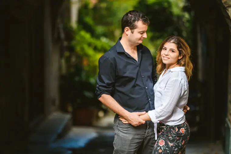 Couple smiling in dappled light against dark green foliage