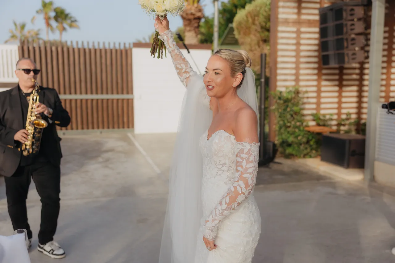 Saxophonist playing as the bride raises her bouquet on arrival at the reception