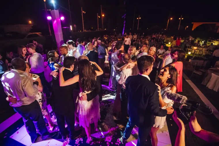 Packed dance floor of guests under purple and pink lights