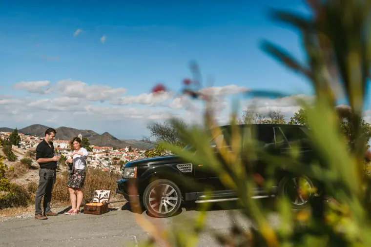Couple standing by a 4x4 overlooking Lefkara village and hills