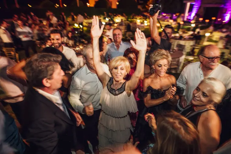 Older guests dancing with arms raised among the crowd