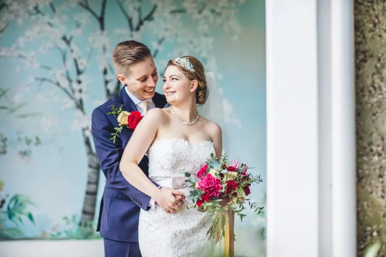 Sarah and Charlie smiling together beside a painted tree mural