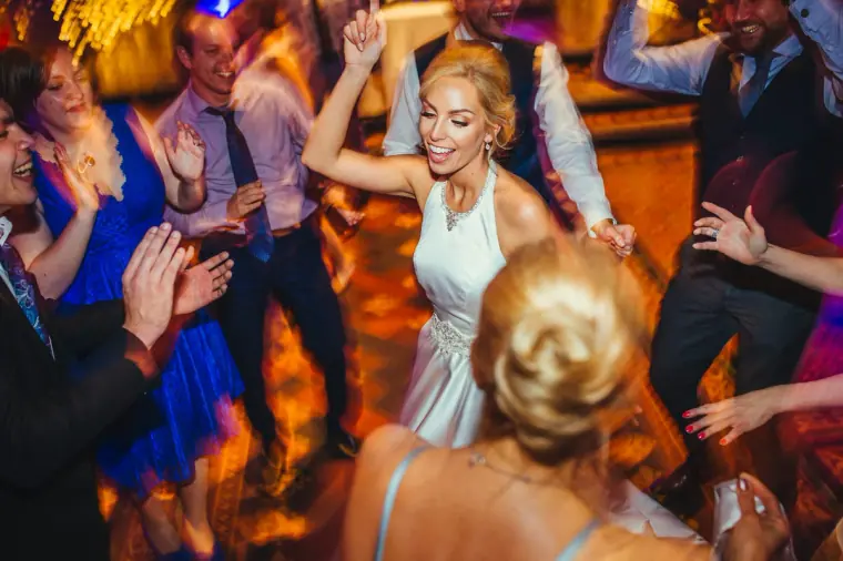 Bride dancing with arms in the air among her guests