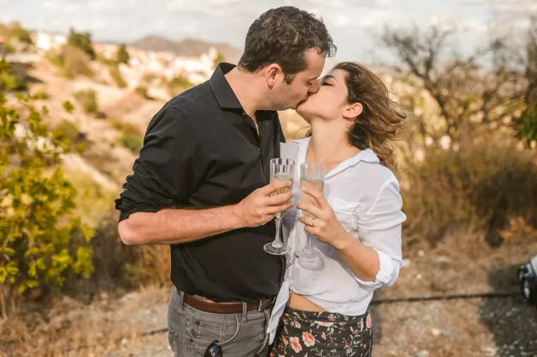Couple kissing with glasses of fizz on a hillside above Lefkara, Cyprus