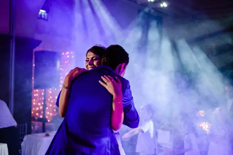 Couple hugging during their first dance under purple and blue disco lights