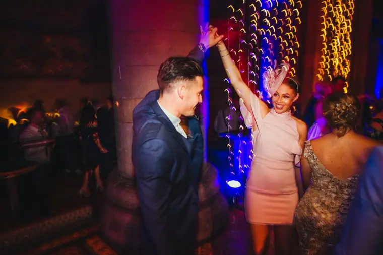 Guest twirling a partner on the dance floor beside a stone pillar