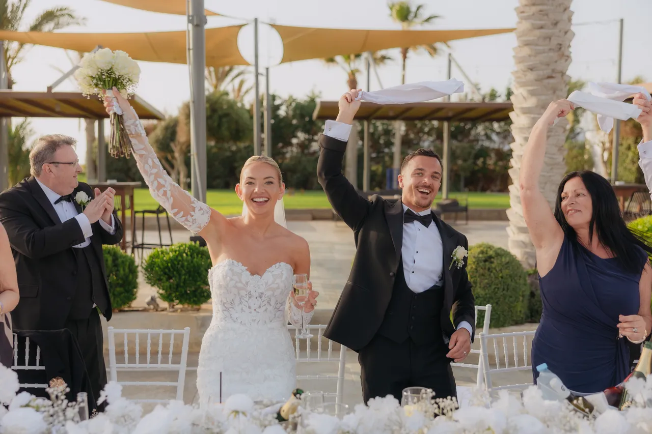 Newlyweds waving napkins above their heads at the top table