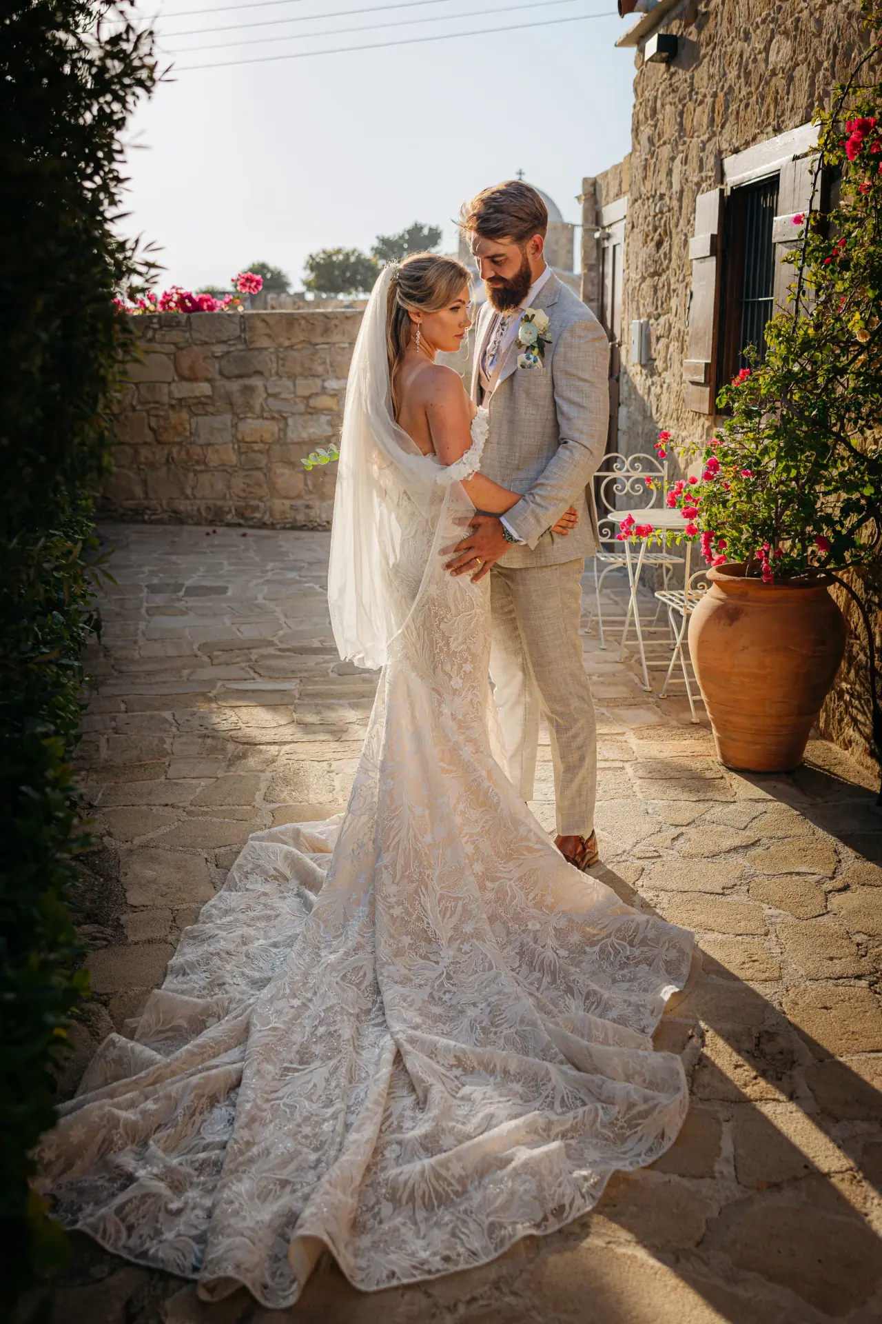 Annie and Iain in a stone courtyard with terracotta pots, her train spread out