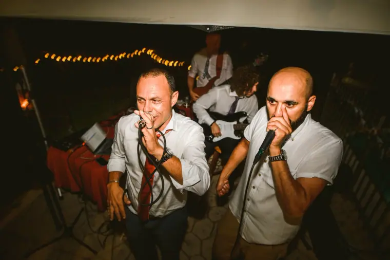 Two guests singing passionately into microphones at an evening reception, Vasilias Nikoklis Inn