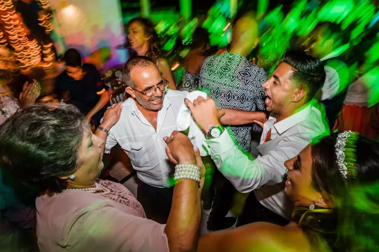 Guests dancing wildly under green party lights at Anassa