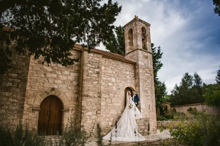 Bride and groom outside an old stone church with a bell tower