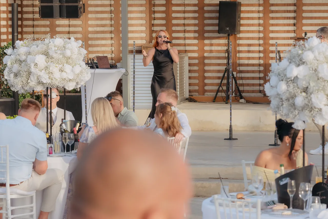 Singer performing for guests among tall white floral arrangements