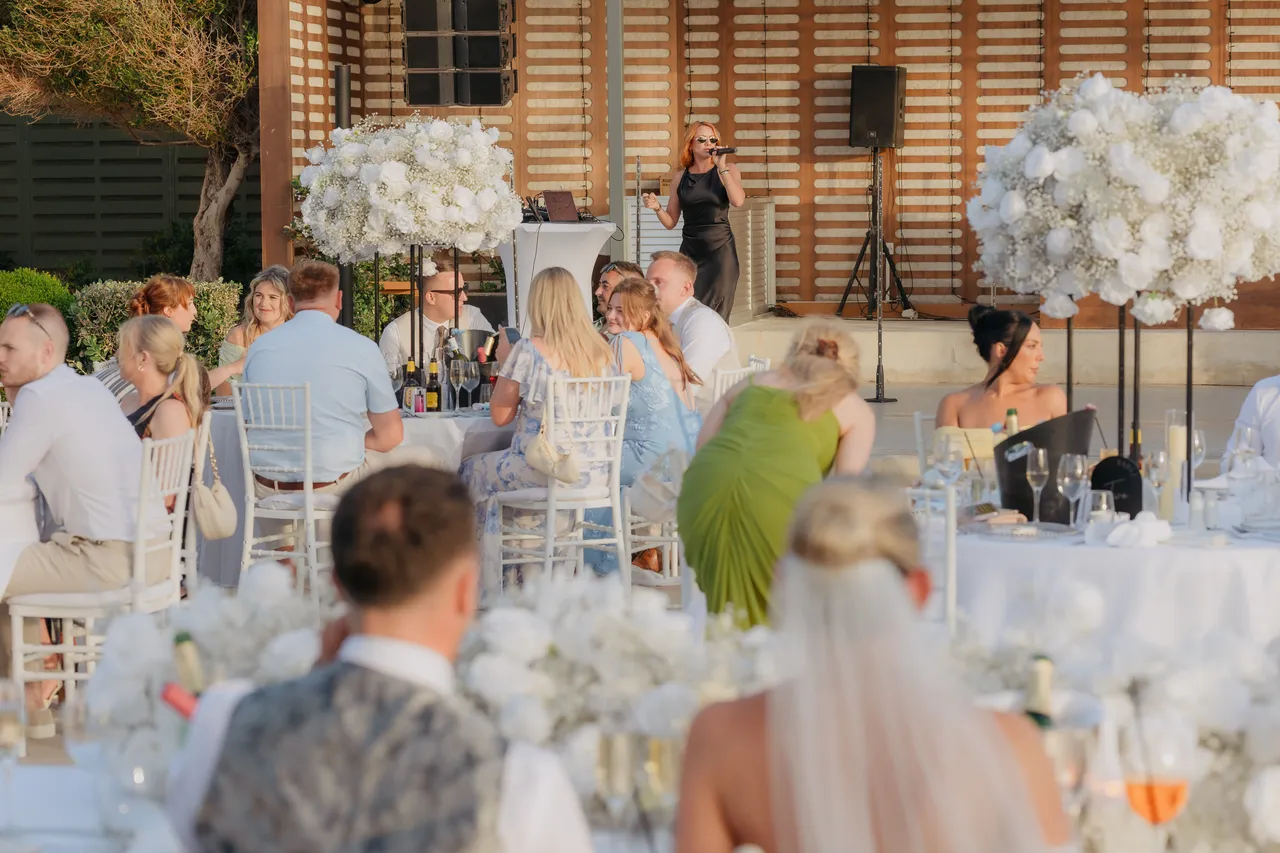 Guests at their tables listening to a singer at the reception