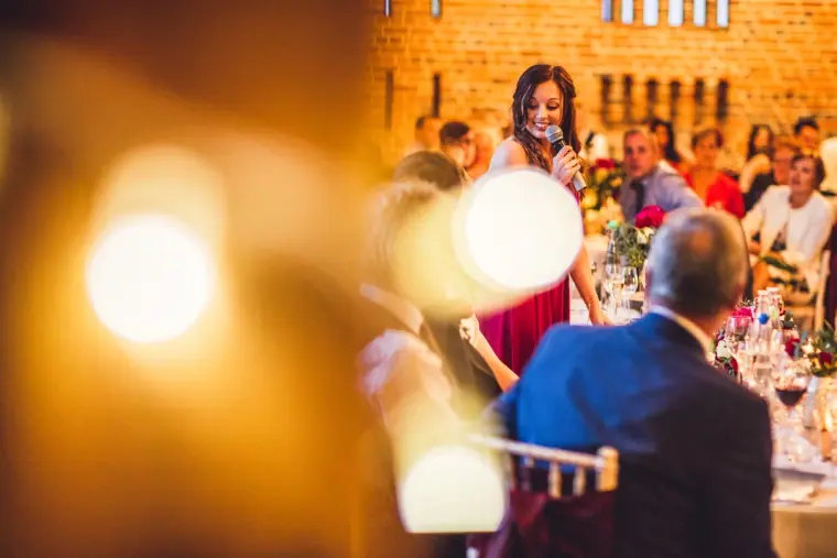 Bridesmaid giving a speech, seen past glowing bokeh lights