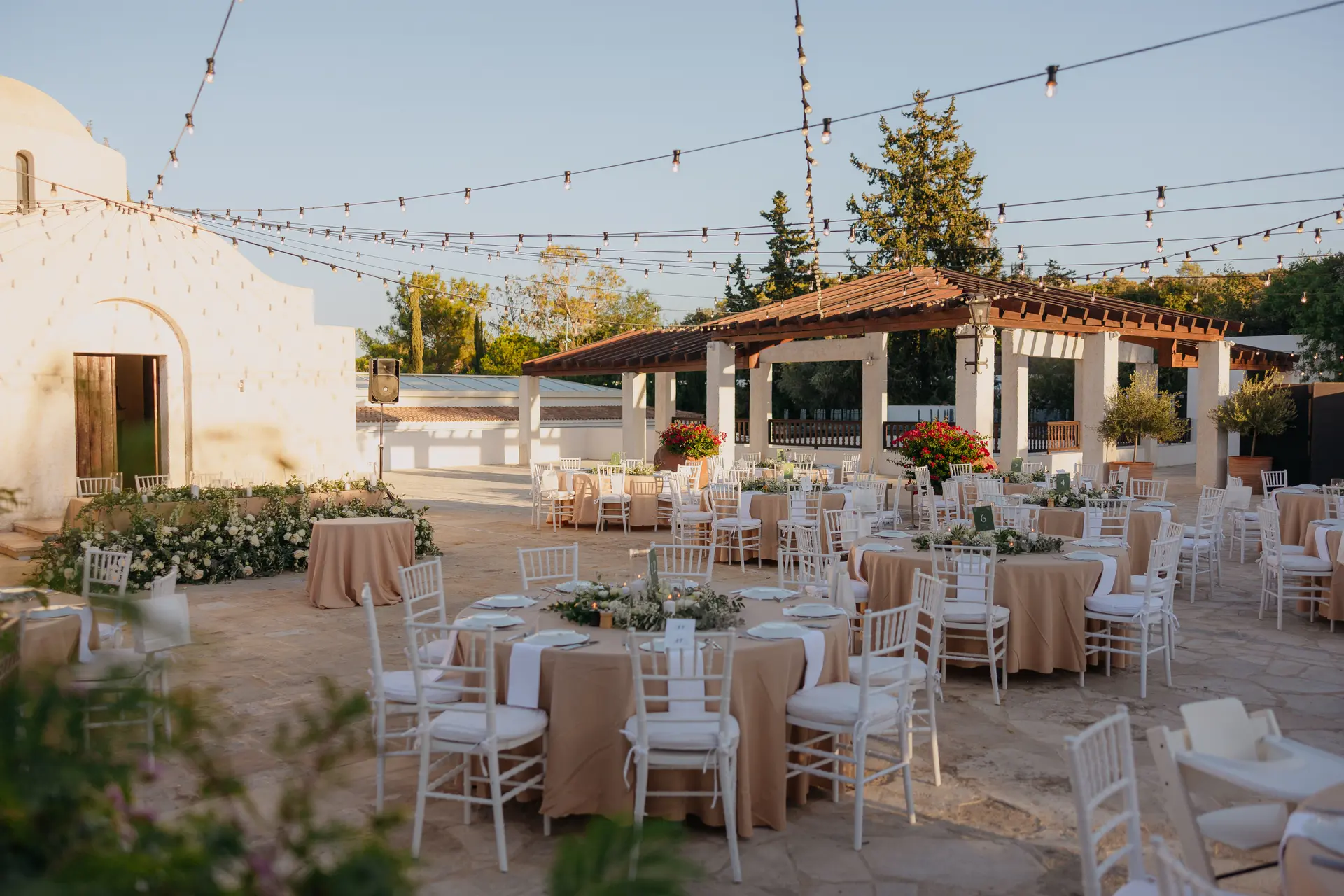 Reception tables set in the courtyard beneath festoon lights and a pergola at Anassa