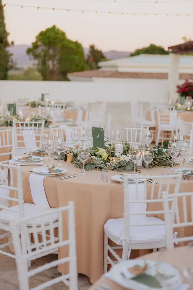 Reception table set with white chairs and glassware in the evening light