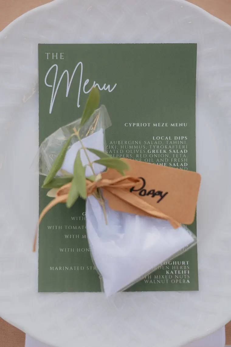 Green menu card with an olive sprig and handwritten name tag on a white napkin