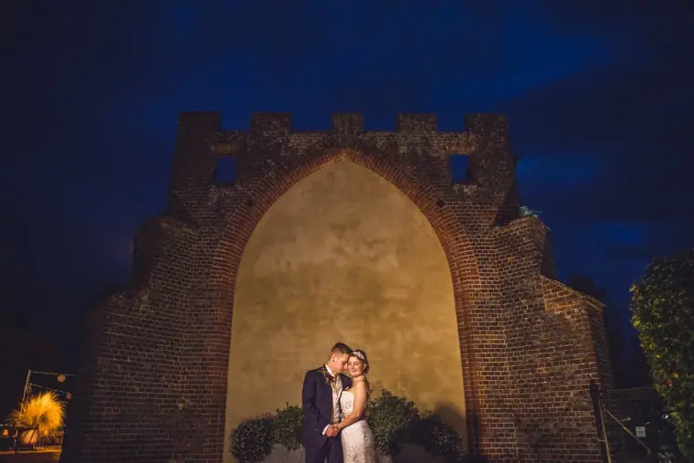 Sarah and Charlie kissing beneath the lit Gothic arch at night, Wasing Park