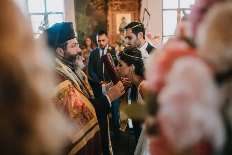 Orthodox priest leading the ceremony as the couple stand with guests, Limassol