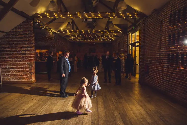 Flower girl twirling on the barn dance floor beneath fairy lights