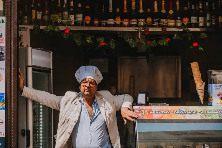 Chef in a white hat posing proudly at the counter of a small shop in Sorrento