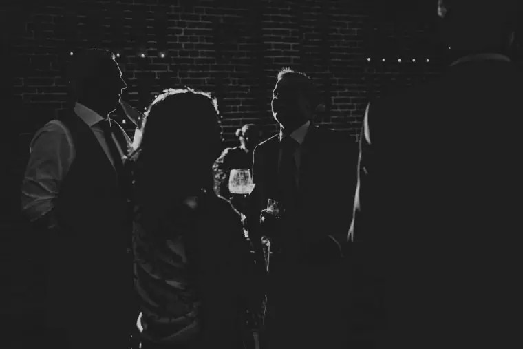 Black-and-white photo of guests silhouetted against a light on the dance floor