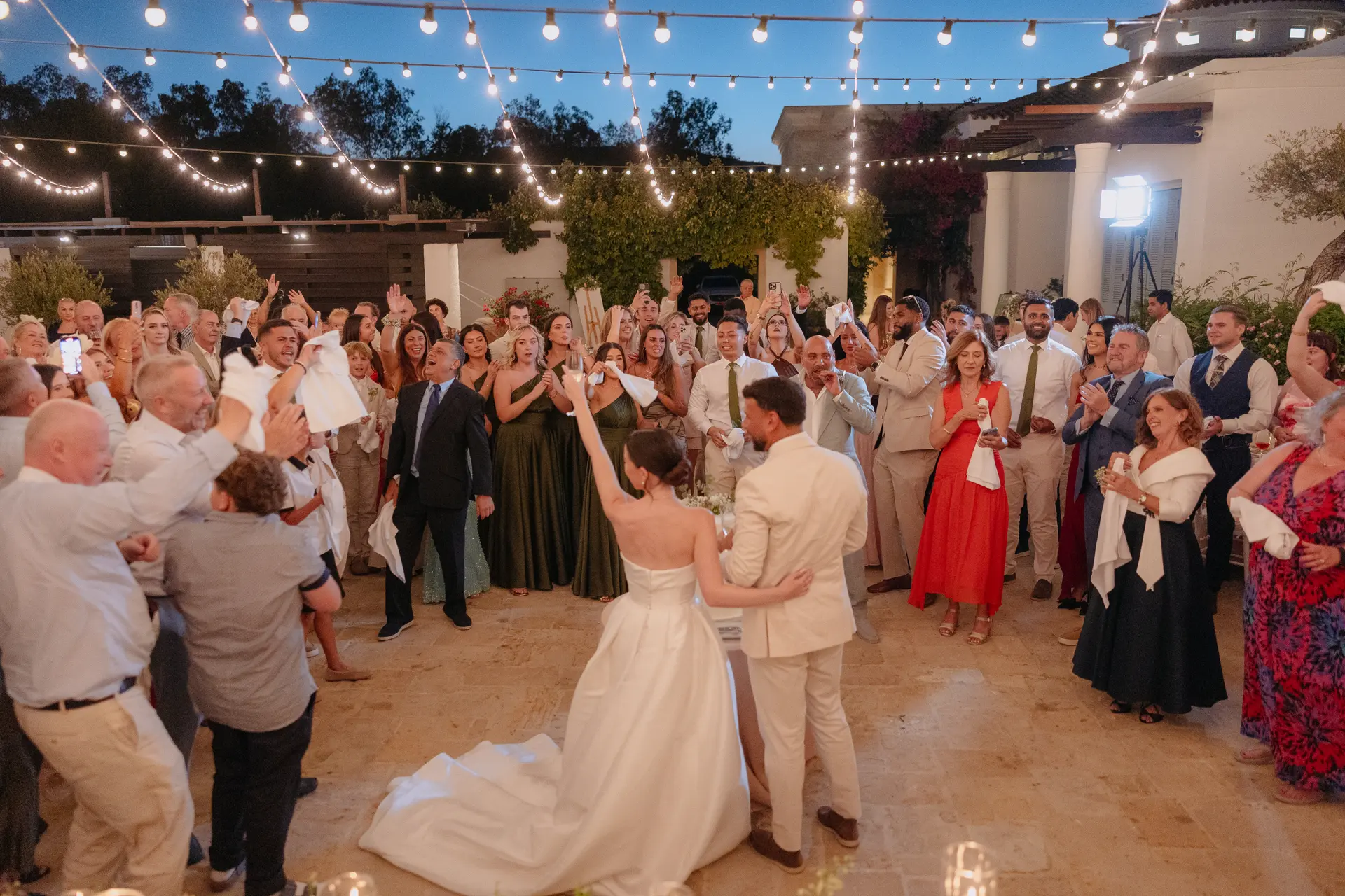 Poppy and Andrew's first dance surrounded by guests under festoon lights