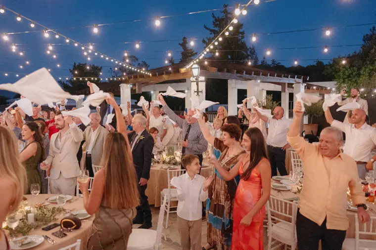Guests waving napkins under festoon lights as the couple arrive