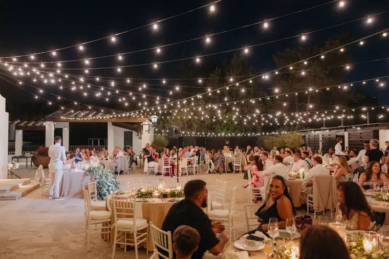 Wide view of the candlelit reception beneath festoon lights