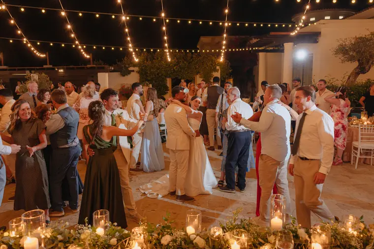 Guests dancing hand in hand around the courtyard under festoon lights