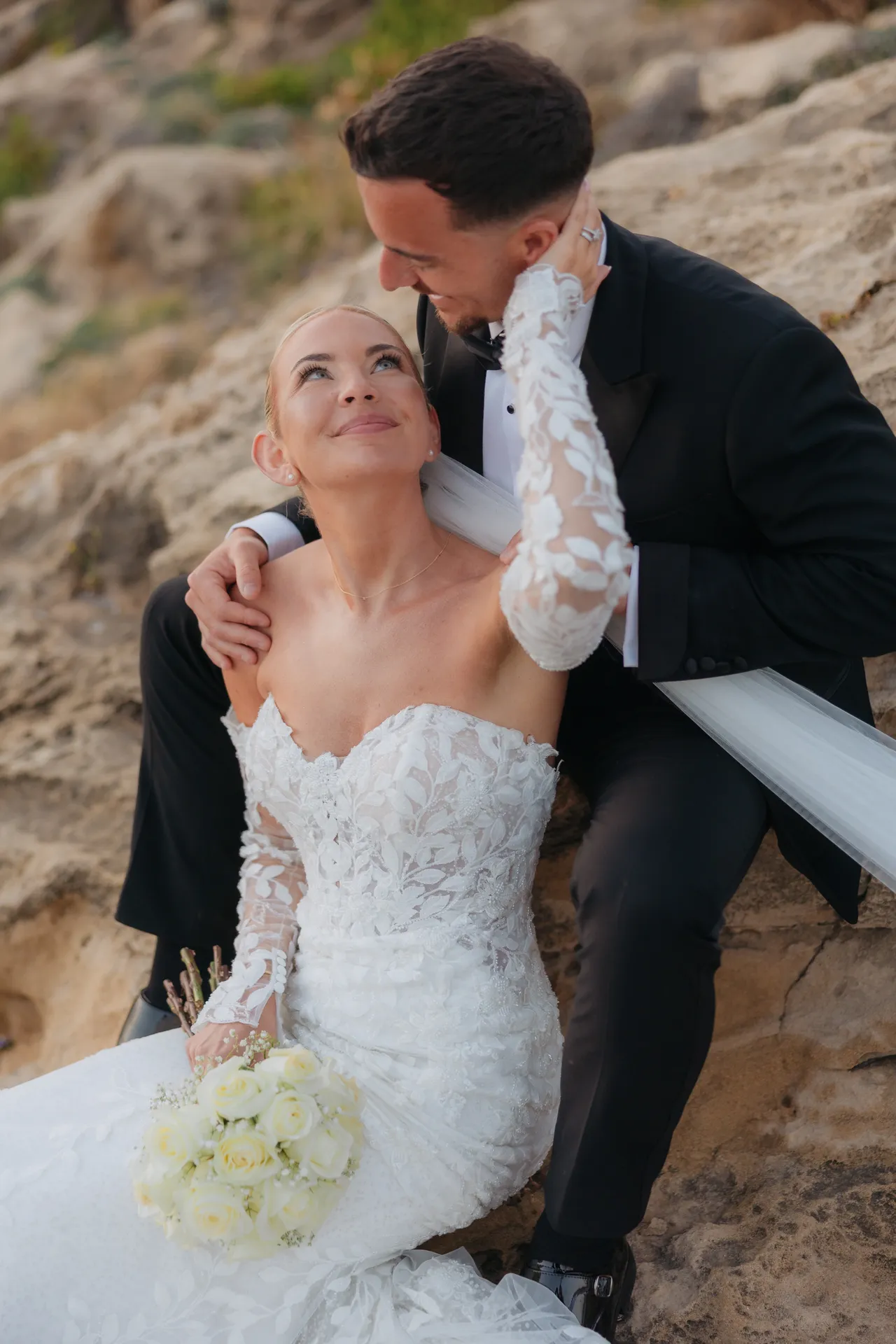 Groom kissing his bride's forehead as she looks up smiling