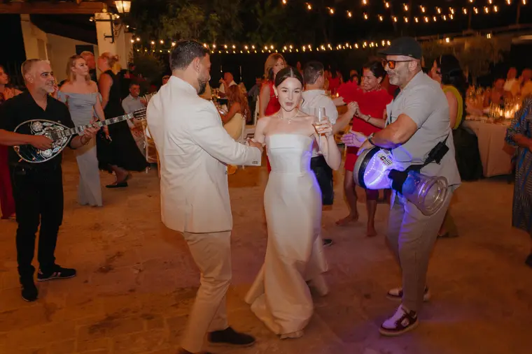 Poppy and Andrew dancing as a musician plays the bouzouki beside them