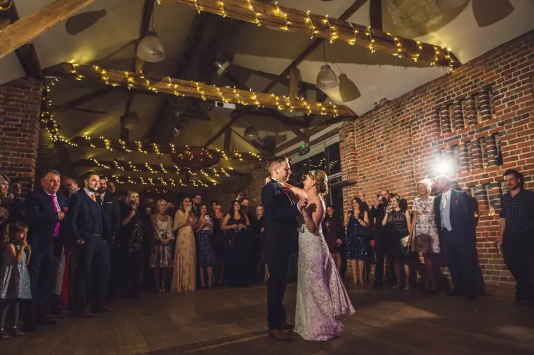 Sarah and Charlie's first dance as guests gather around in the barn