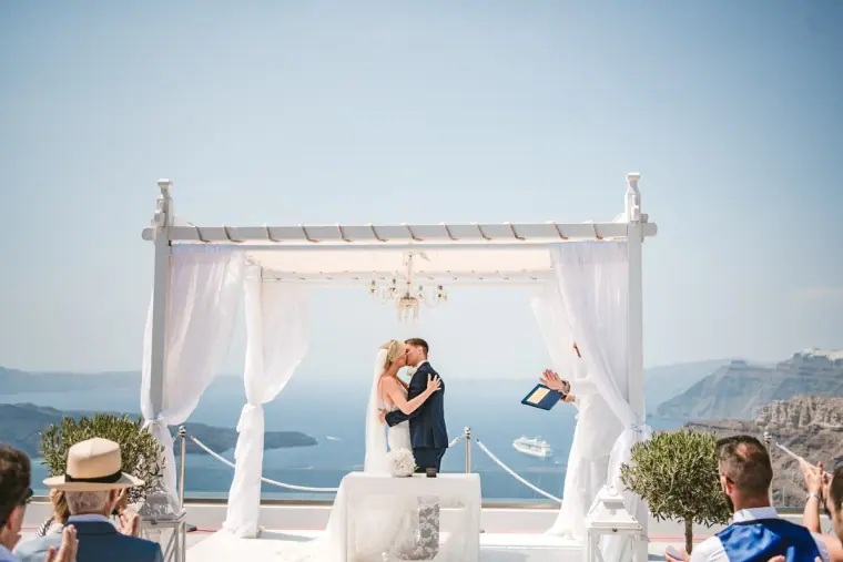 Couple kissing under a white draped canopy overlooking the sea from a clifftop terrace