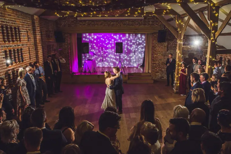 Wide view of the first dance with a purple-lit stage and guests all around