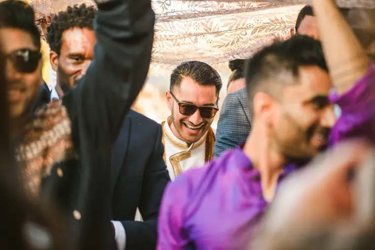 Guests in sunglasses and kurtas celebrating as the groom's party arrives
