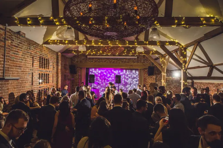 Guests crowding the dance floor in front of the glowing purple stage