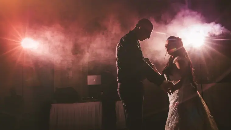 Silhouetted couple sharing their first dance in pink haze and spotlights