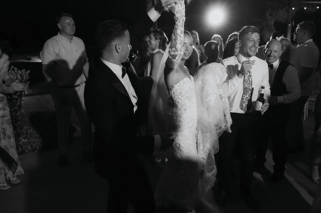 Black-and-white photo of guests dancing around the bride and groom