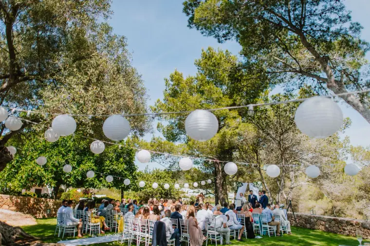 Outdoor reception under pine trees hung with white paper lanterns at Can Curreu, Ibiza