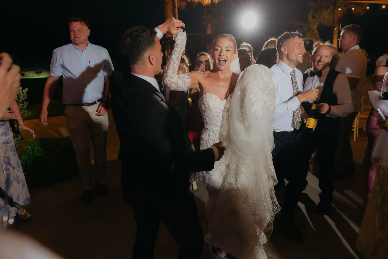 Bride and groom dancing among guests at night