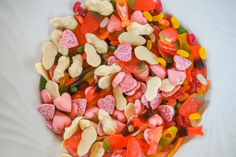 Pile of colourful sweets and jelly hearts on a white plate