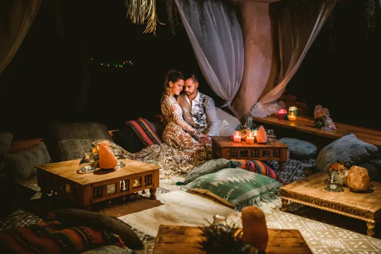 Couple relaxing in a candlelit lounge area with cushions, rugs and low tables